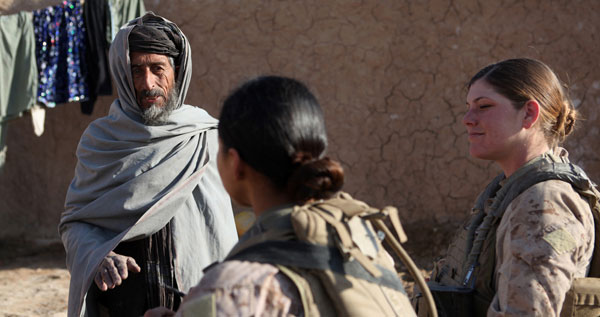Two female military troops speak with a man in Afghanistan